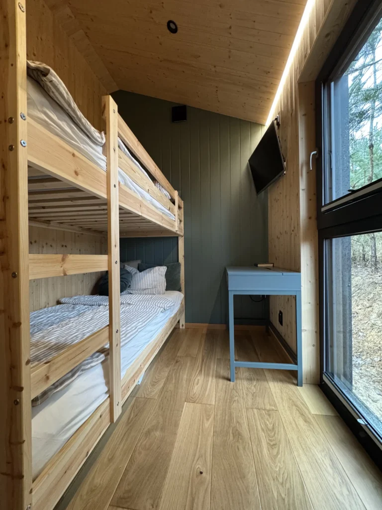Pokój w domku mobilnym DROZD, wyposażony w łóżko piętrowe, telewizor i biurko
