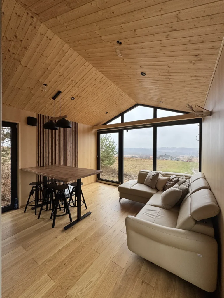 Przestronny salon z aneksem kuchennym w domku mobilnym DROZD z dużym, panoramicznym oknem