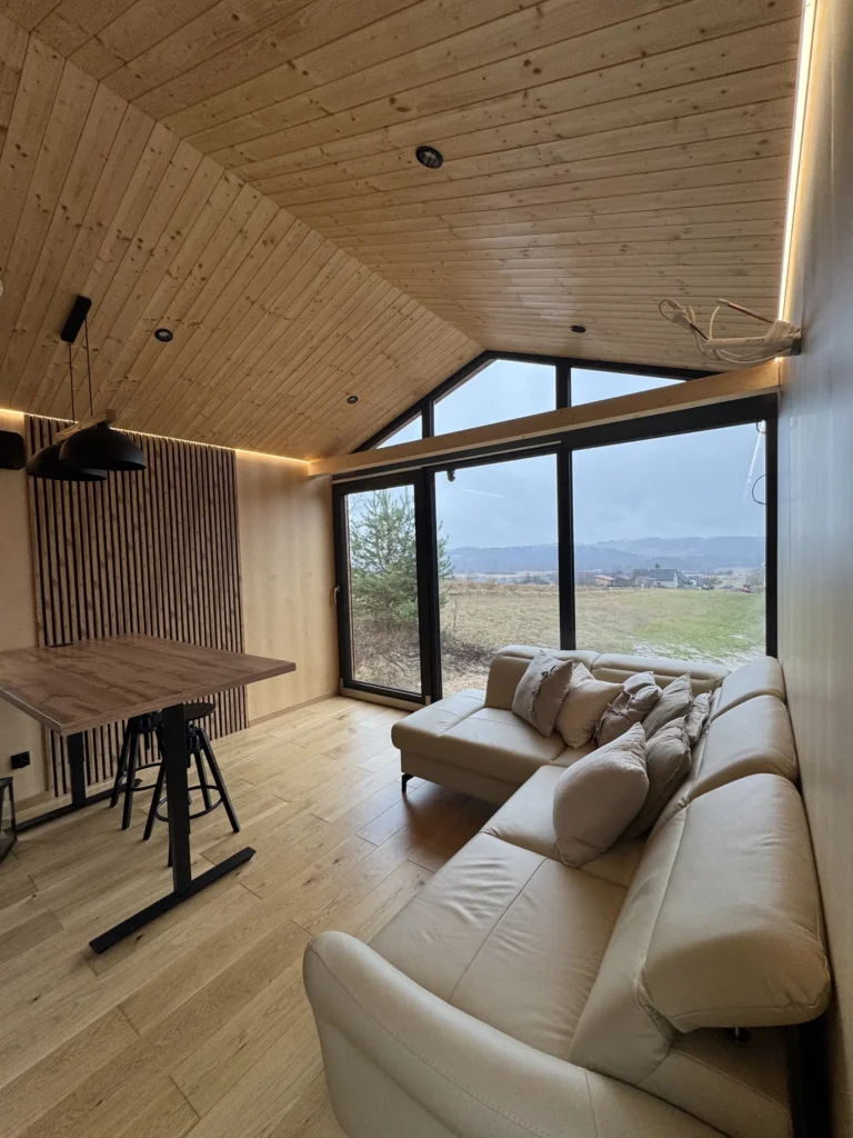 Przestronny salon z aneksem kuchennym w domku mobilnym DROZD z dużym, panoramicznym oknem